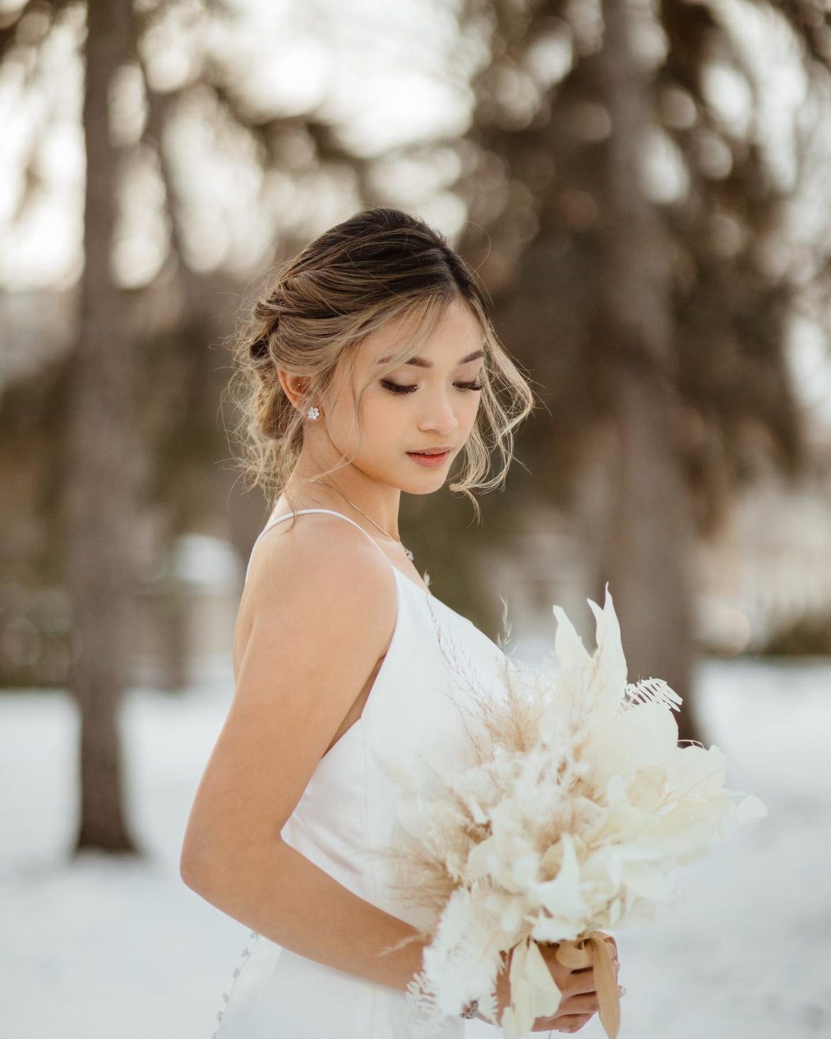 A close-up of a beautiful asian bride in a white dress with an up-do hairstyle.